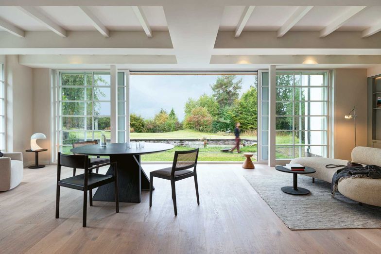 Im Wohn-Essbereich öffnen sich grosszügige Fensterfronten beinahe vollständig und bringen nicht nur Licht hinein, sondern verbinden den Innenraum fliessend mit dem denkmalgeschützten Garten. Beistelltisch, Esstisch- und Stühle: Boffi; Sofa «Honoré» von Elisa Ossino für De Padova.
