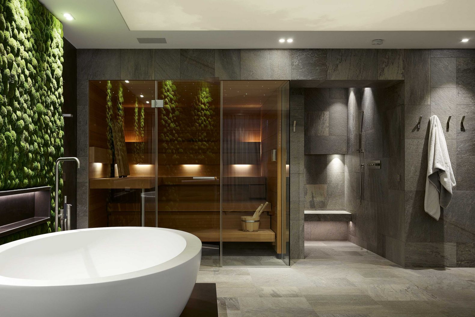 Viel zu schön, um im Keller zu stehen: Der Spa-Bereich nimmt die dritte Etage eines Einfamilienhauses ein. Neben der Wand aus Moos sind die freistehende Wanne, die offene, begehbare Dusche und die Sauna «Shape» die Highlights des privaten Wellnessbereichs. Foto: Achim Venzke. KLAFS SAUNABAU.