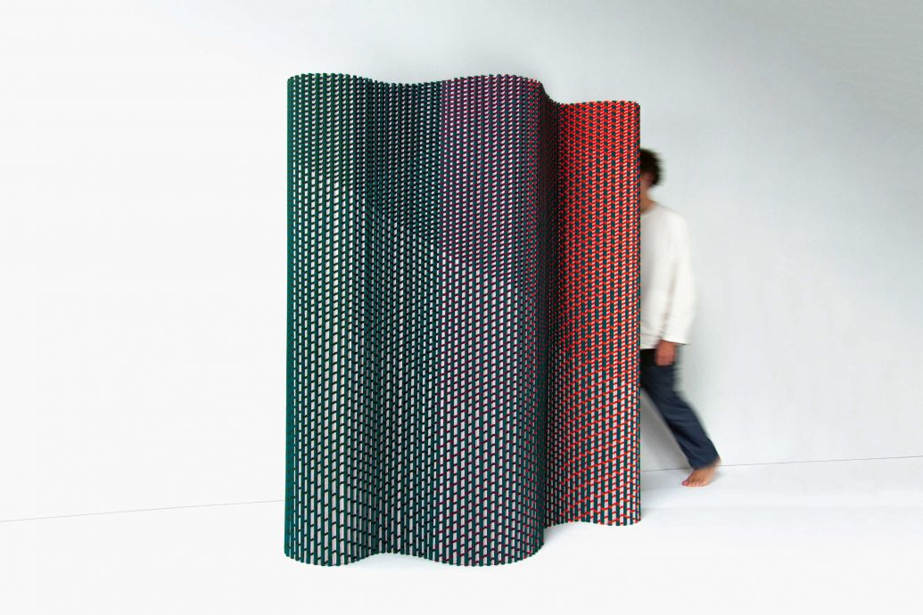 Textilien gehören zu den beliebtesten Materialien, um Räumen Wärme, Komfort und Leichtigkeit zu verleihen. Oft werden sie jedoch auf eine Art und Weise verarbeitet, die keine Rücksicht auf unsere Umwelt nimmt. Mit ihrem textilen Paravent, dem «Pleated Partition Screen», geht die Produkt- und Textildesignerin nun einen völlig neuen, umweltfreundlichen Weg und zeigt, dass Textilien auch ohne Bindemittel, Klebstoffe oder harte Materialien versteift werden können. Für ihren selbsttragenden, wellenförmigen Raumteiler, der ausschliesslich aus Textilien besteht, hat sie traditionelle Falttechniken neu interpretiert. FENNAVANDERKLEI.NL