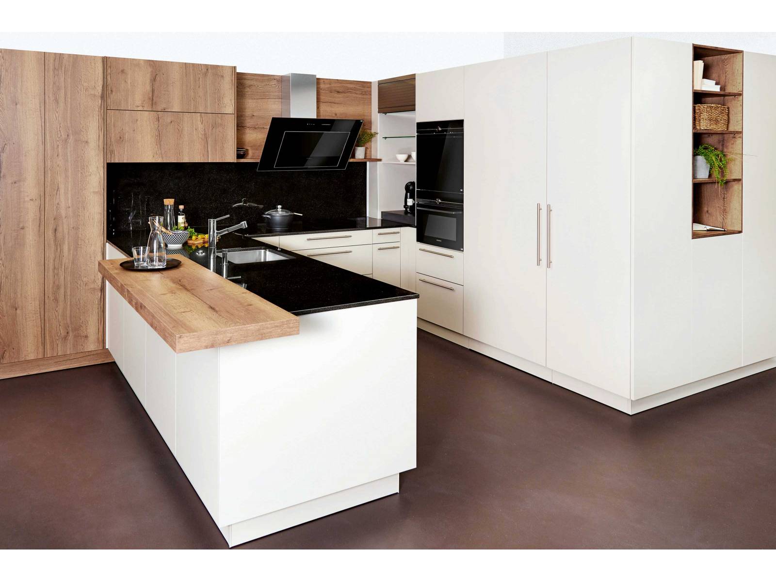 Holz, Granit und schlichtes Weiss lassen diese Küche modern und wohnlich daherkommen. Ein technisches Highlight ist die Dunstabzugshaube, deren Leistung sich nicht nur am Kochdunst anpasst, sondern bei Bedarf auch bequem per Handy oder Tablet gesteuert werden kann. SABAG.