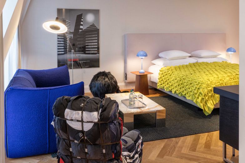Das Studio ist mit Werken aus der Stiftung Kunstsammlung Teo Jakob ausgestattet. Zu sehen sind unter anderem seltene Entwürfe für Künstlerplakate, die im Laufe der Jahre von lokalen und internationalen Künstlern als Werbeplakate für Teo Jakob gestaltet wurden. Das Boxspringbett stammt vom Hersteller Schramm GmbH, der Teppich vom Atelier Ruckstuhl, der 1970 entworfene Fellhocker «Ron Ron» der Designerin Marion Baruch ist von Gufram und die Stehleuchte «Type 600» ist ein Entwurf aus dem Jahr 1951 des Designerpaares Rosmarie und Rico Baltensweiler. Das Sofa «Bambole» des Herstellers B&B Italia steht symbolisch für das Jahr 1972. Der Beistelltisch «NMSH» aus dem Jahr 2023 des Designkollektivs NM3 fügt sich modern ein.