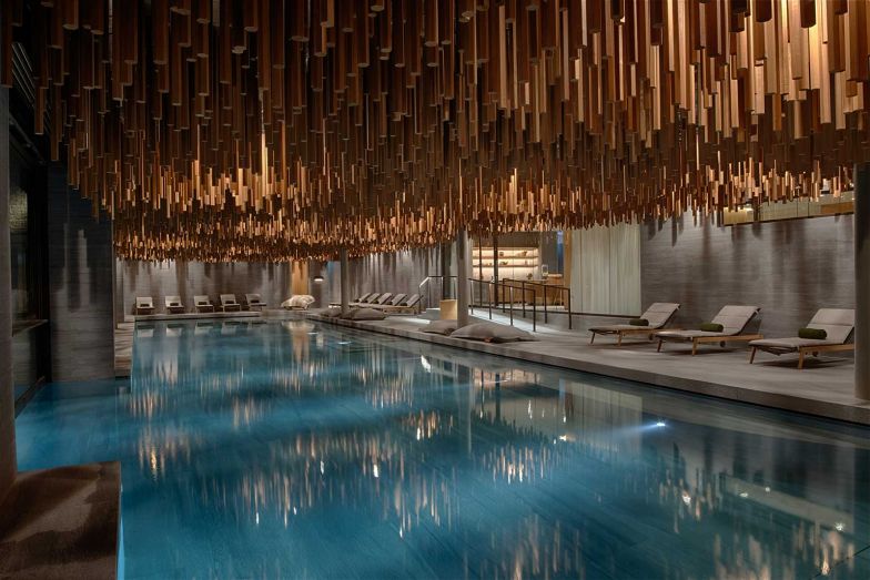 Das Herzstück des Spa-Bereichs ist das Hallenbad, gestaltet wie eine natürliche Grotte mit Steinwänden und einer kunstvoll geschnitzten Holzdecke, die ein faszinierendes Lichtspiel erzeugt.