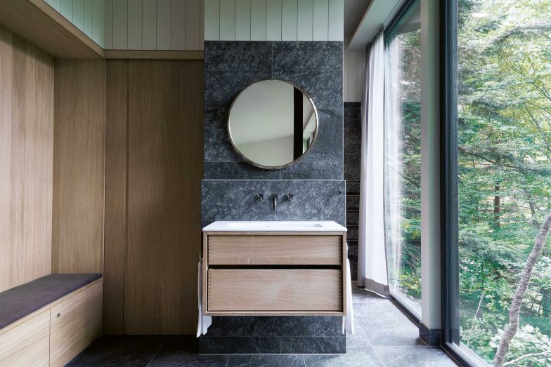Badzone im Steinhaus. Rechts der grosszügige Duschbereich, links Toilette und Garderobe. Das Fichtenholz wurde in der Umgebung geschlagen, der Stein stammt aus einem Steinbruch weiter oben im Tal. Armaturen, Waschbecken: Duravit. Foto: Andrea Diglas Photography.
