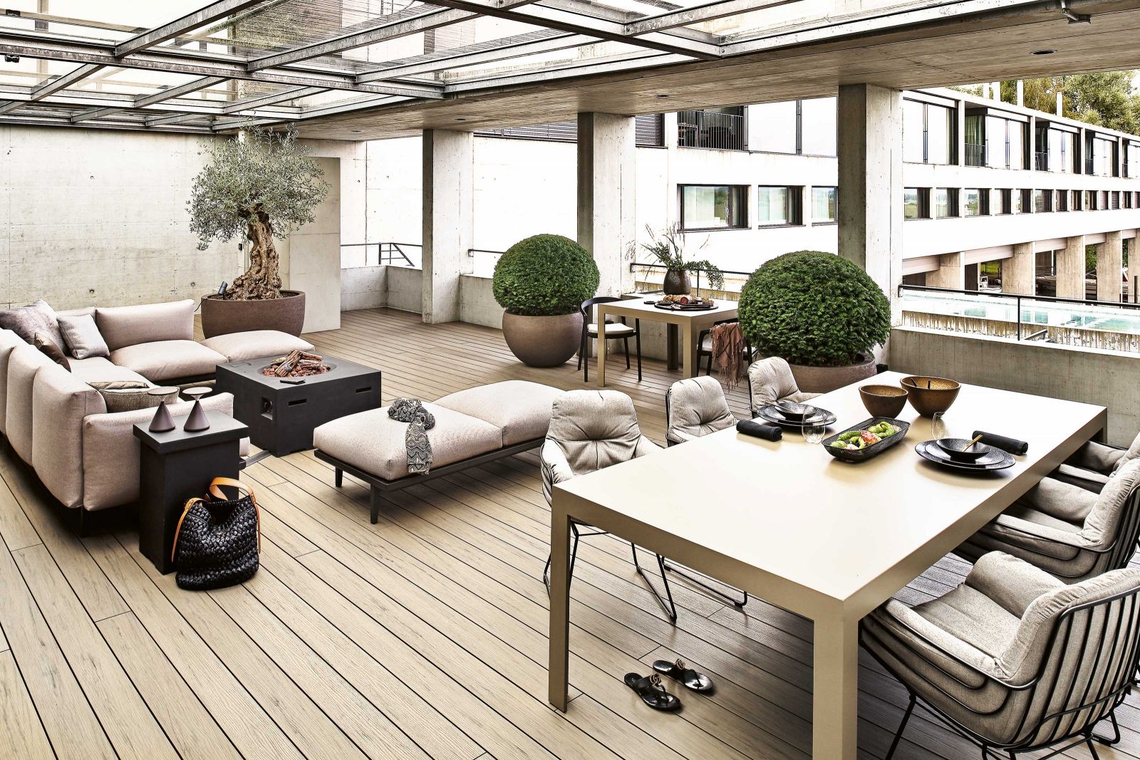 Im Sommer wird die überdachte Terrasse zum zweiten Wohnzimmer. Auch hier kombinierte die Interior-Designerin viele Braun- und Cremetöne. Mittig platzierte sie einen Lounge-Bereich um die Gasfeuerstelle, das Sofa und die Liege sind von Kettal; die Stühle «Leyasol» von Freifrau.